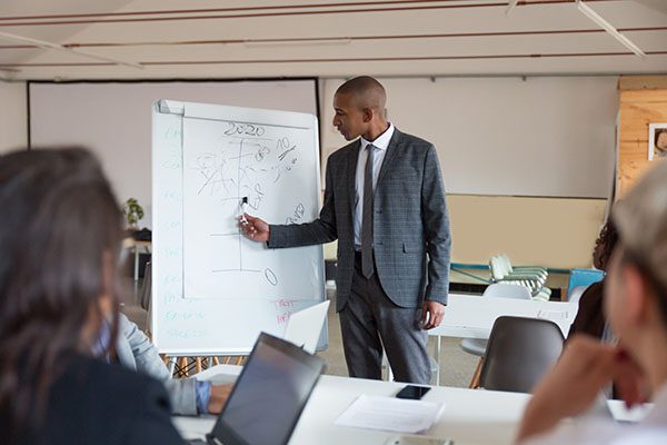 confident-speaker-talking-pointing-whiteboard_74855-4122